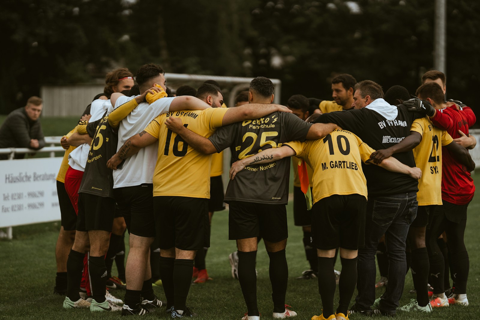 Association football players gathered in a team huddle on the pitch